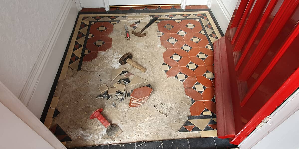Detailed view of damaged Victorian tiles with cracks and missing pieces before restoration